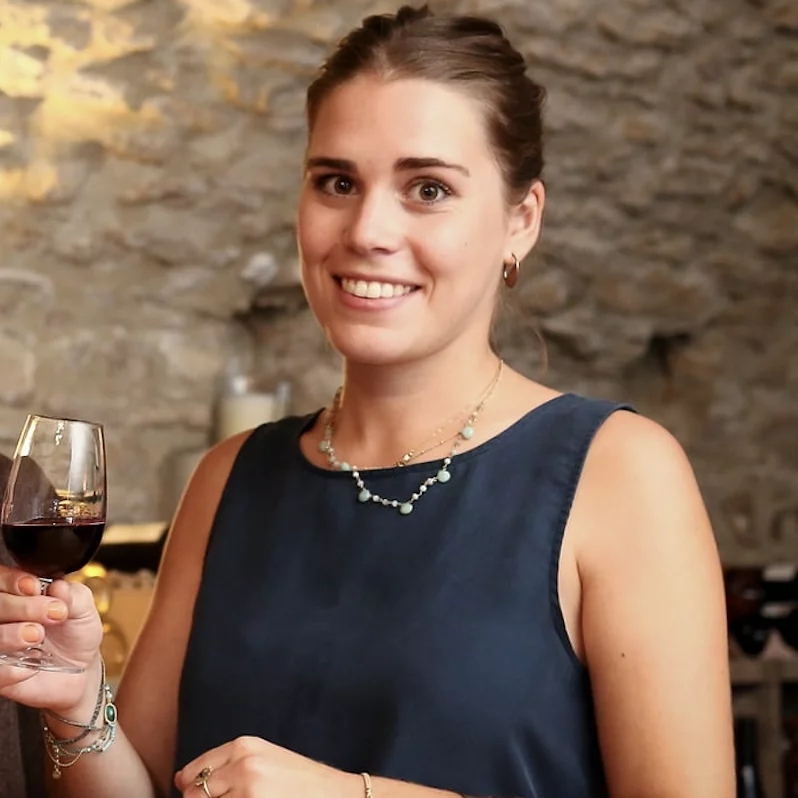 Portrait souriant de la fondatrice de Vin & Van tenant un verre de vin rouge.